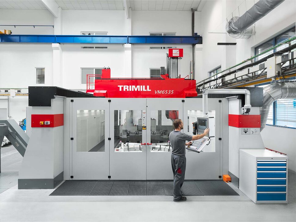 A large CNC machining center of the Trimill VM6535 brand is being programmed by a machining technician at the control console to subsequently carry out CNC machining operations.