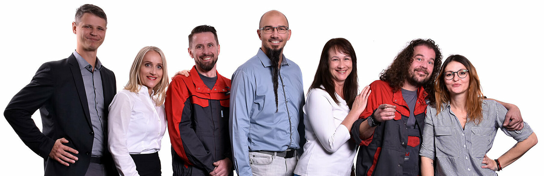 A group of seven weba Werkzeugbau employees from various departments, posing for a group photo. Two are wearing typical work clothing, symbolizing the manufacturing areas. Two others are in formal business attire, representative of management or office roles. The remaining three employees are dressed in a casual look, indicating creative or less formal positions within the company. The diversity of clothing styles reflects the range of job roles and the inclusive work culture at weba. The image showcases the work culture and jobs in Steyr at weba Werkzeugbau.