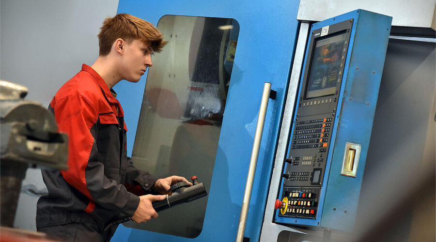 Das Bild zeigt einen Lehrling in der Werkzeugbautechnik, der konzentriert eine Erodiermaschine bedient. Seine Hände sind geschickt damit beschäftigt, die Maschine zu steuern, während er den Bearbeitungsprozess überwacht. Die Szene vermittelt den Eindruck von Lernbereitschaft und praktischer Erfahrung im Umgang mit hochpräzisen Werkzeugmaschinen bei der Herstellung qualitativer Stanz- und Umformwerkzeuge..