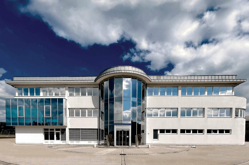 Exterior shot of the administrative wing of weba's development center in Dietach under a blue sky with clouds.