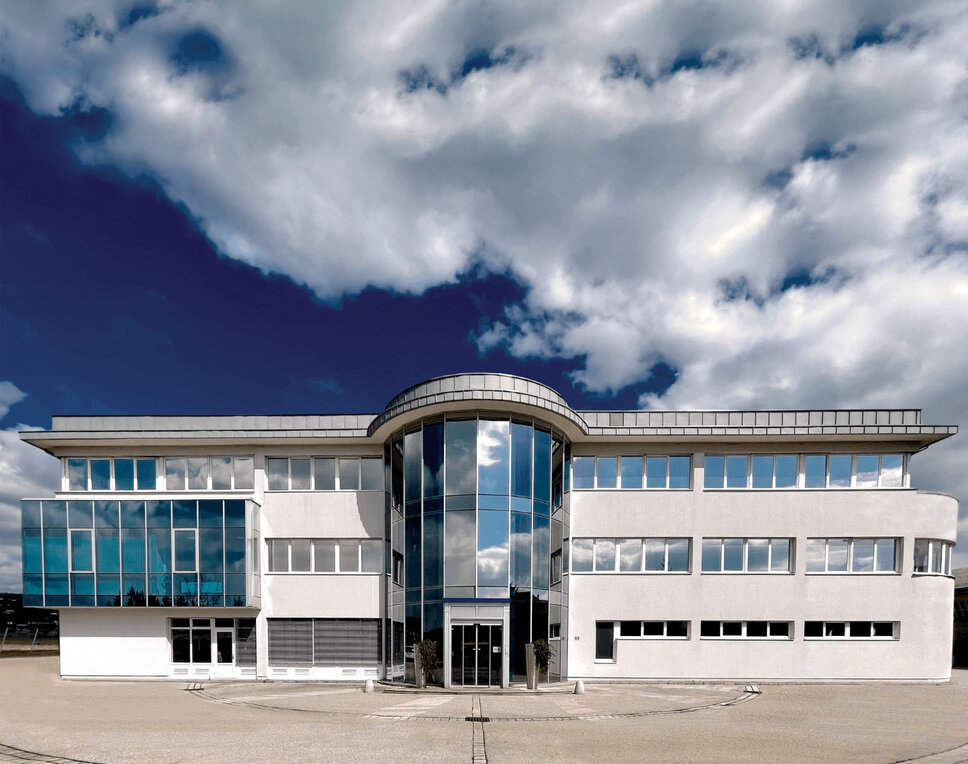 Exterior view of the administration building of the weba development center in Dietach under a blue sky with clouds.