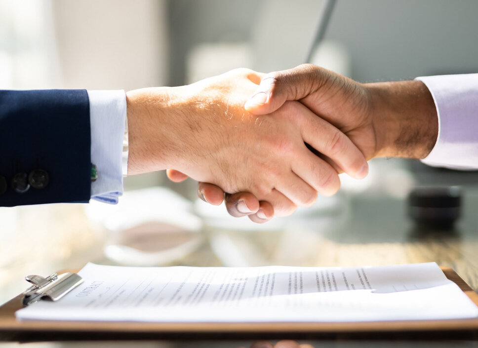  Handshake between two business professionals over a contract, symbolizing the partnership between weba Werkzeugbau and Meprotec in the field of process technology for press hardening.