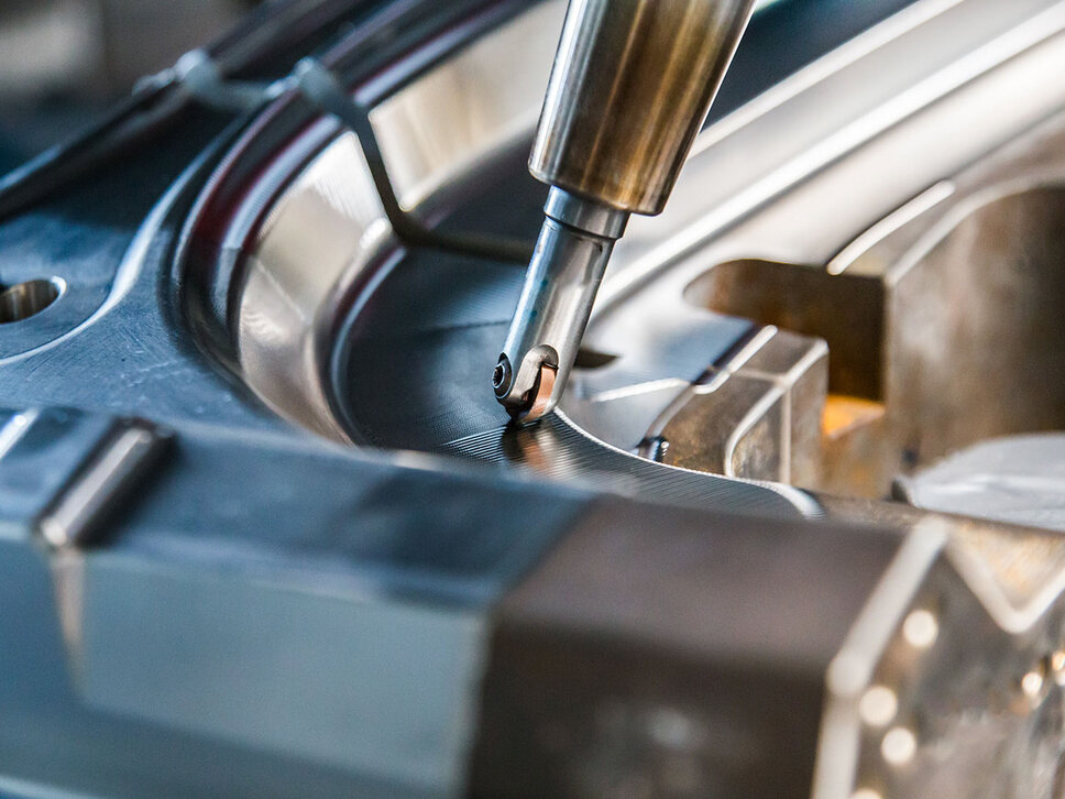 Close-up of a CNC machining operation; the milling head is machining a complex shape from steel.