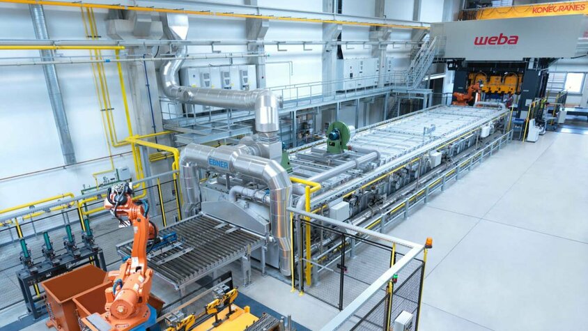  Gesamtaufnahme der automatisierten Anlage für die Warmumformung in weba Olomouc, beginnend bei der Signier- und Markierstation, über den Rollenherdofen und die Roboter bis hin zur Umformpresse.