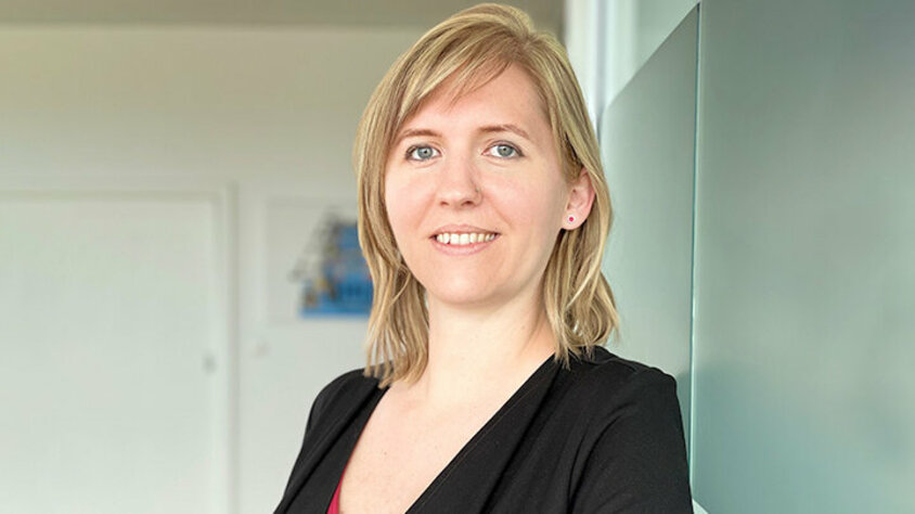 Porträt von Tanja Burghuber, Personalmanagerin bei weba Werkzeugbau, entspannt an einer Milchglaswand in Dietach lehnend, mit einem professionellen und freundlichen Ausdruck, betont durch die weiche Beleuchtung und den verschwommenen Hintergrund. Das Foto wird im Kontaktbereich der Stellenangebote in Steyr von weba Werkzeugbau verwendet.