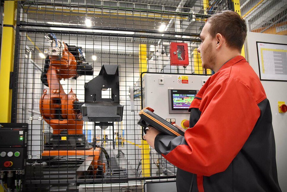 A machining technician programs the automated machining line at weba Olomouc. He concentrates on the transfer gripper while holding a control tablet in his hands.