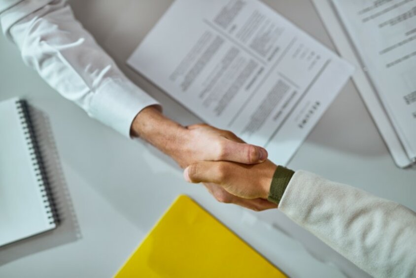 Handshake after successfully reaching an agreement over signed contracts. The image symbolizes the contract signing for a job entry in Steyr at weba Werkzeugbau.